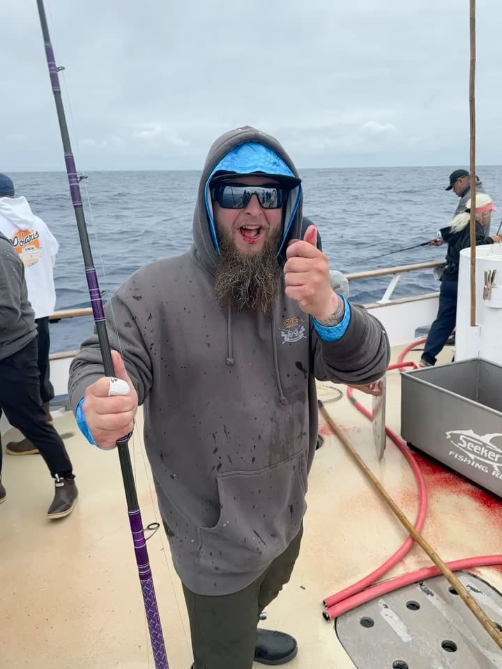 Angler giving a thumbs-up while the deck buzzes with night fishing